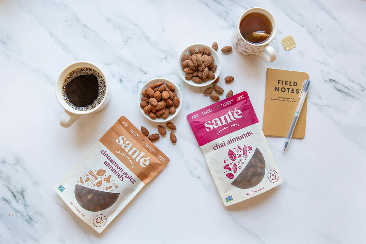 Santé Nuts Blog - Cinnamon Spice Almonds and Chai Almonds on a countertop, paired with cups of coffee and tea